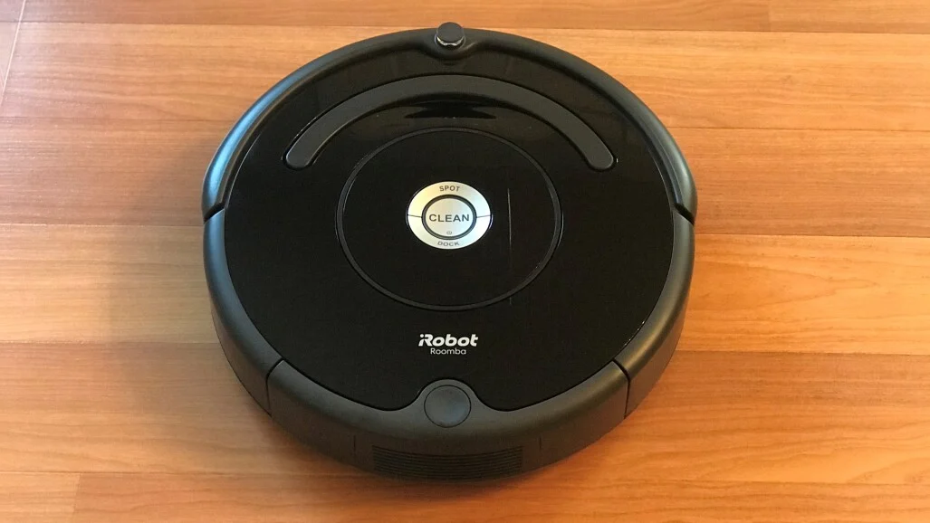 A Roomba robot vacuum resting on a wooden floor
